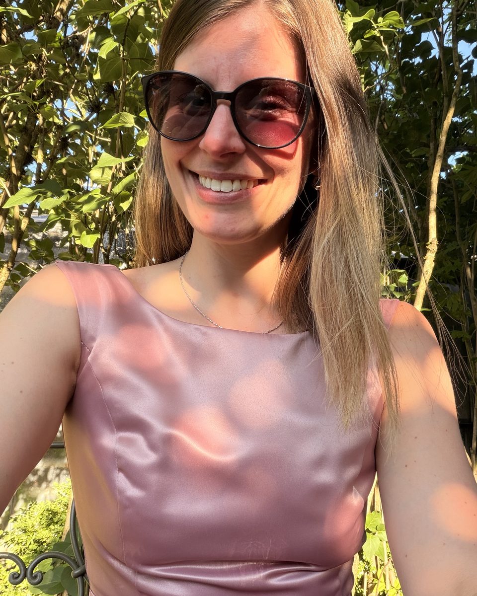 Cosima Karmann lächelnd im Garten, im rosafarbenen Kleid